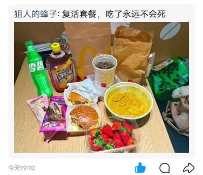 这是一张网友分享的美食晒图，画面里的木质桌面上摆放着瓶装雪碧、瓶装冰红茶、两杯带盖冰饮、两个麦当劳汉堡、一盒新鲜草莓、一碗黄色糊状餐食、两盒巧乐兹冰淇淋，后方还放置了两个麦当劳的牛皮纸打包袋，图片上方配文玩梗称这些食物是“复活套餐，吃了永远不会死”，用夸张的表述调侃这套丰盛餐食能带来极强的满足感，吃完仿佛能恢复全部活力。