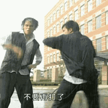 图片展示了台剧《紫禁之巅》中的经典名场面：两位男性角色在教学楼前的雨中摆出格斗姿势，看似激烈对峙，实则动作如同尬舞。画面底部配有白色字幕“不要再打了”，还原了女主劝架时的台词。该场景因“打架像跳舞”的荒诞感成为网络梗，常用于调侃无意义的争执或劝架无效的尴尬局面。