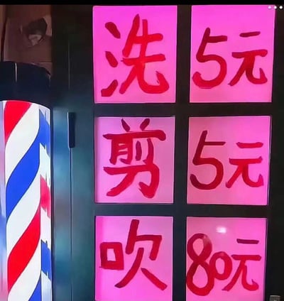 图片展示了一家理发店的价格牌，背景为粉色面板，红色手写体文字标注服务价格：洗5元，剪5元，吹80元。左侧可见经典红白蓝条纹的理发店旋转灯。价格表中吹头发80元与洗剪5元形成鲜明对比，显得十分夸张，可能用于搞笑或吐槽理发店收费不合理。