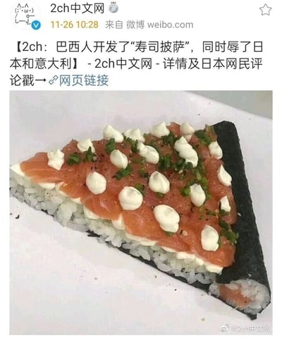 这是一张来自微博用户“2ch中文网”的社交媒体截图，发布时间为2020年11月26日10:28。截图主体是一款名为“寿司披萨”的融合料理，它被做成了披萨的三角切片样式，外层包裹着黑色海苔，底层是压实的寿司饭，饭层上方铺着新鲜的三文鱼片，表面挤有多颗白色奶油状酱料，还撒有绿色碎香草和黑胡椒碎作为调味。配文内容为“【2ch：巴西人开发了“寿司披萨”，同时辱了日本和意大利】-2ch中文网-详情及日本网民评论戳→网页链接”，意思是这款结合了日本寿司与意大利披萨元素的料理，颠覆了两种传统美食的常规形态，被认为“冒犯”了日意两国的饮食文化，相关详情可点击附带链接查看日本网民的讨论内容。