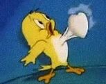图片中是经典卡通角色小黄鸟Tweety Bird，它有着黄色的羽毛和橙色的脚，正处于动态姿势中，嘴巴张开，似乎在吐出一团白色的、类似棉花或云朵的物体。背景为纯蓝色，突出显示了角色的动作。整个画面充满了动画的活泼感，展现了Tweety Bird在原作中的经典形象。