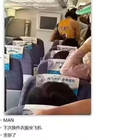 这是一张社交媒体分享的搞笑梗图，画面展示了飞机客舱内部的场景：一名身穿科比·布莱恩特24号黄色球衣的乘客站在座位过道间，而前方多个座椅的头枕巾上都印着“排齐牙齿 改善面形”的牙科广告。图片下方配文“MAN 下次换件衣服坐飞机 求你了”。
这个梗的笑点来自谐音：“科比”的发音和“磕鼻”相近，结合头枕巾上的牙科面形矫正广告，形成了仿佛广告在调侃这位乘客的趣味巧合，让人忍俊不禁。