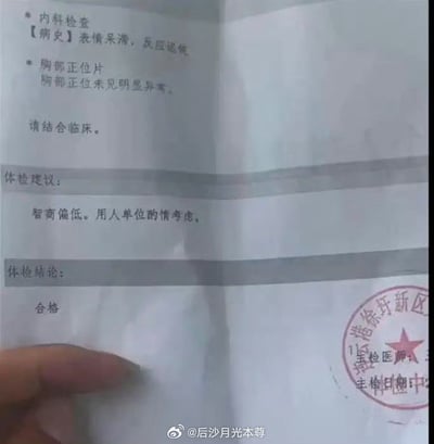 这是一张实拍的体检报告图片，报告内容存在明显的矛盾性：内科检查病史记录显示受检者“表情呆滞，反应迟钝”，体检建议明确写着“智商偏低。用人单位酌情考虑。”，但最终的体检结论却标注为“合格”，胸部正位片结果为“未见明显异常”。报告右下角盖有“港徐圩新区”相关的体检专用章，图片底部带有微博用户“@后沙月光本尊”的水印，左下角可见拍摄者的部分手指。这份报告的矛盾内容制造出荒诞搞笑的效果，一边给出负面的评价建议，一边又给出合格结论，逻辑相悖，十分滑稽。