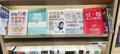 这是一张线下书店货架的实拍照片，上层木质货架上整齐摆放了6本以字节跳动旗下AI工具“豆包”为核心主题的教程类书籍，内容方向涵盖家庭生活辅助、办公效率提升、AI变现赚钱、搭配DeepSeek使用的智能办公技巧等，针对有学习使用AI工具需求的读者群体，覆盖入门到进阶的不同学习阶段；货架右下角贴有“滕州书城 300102”的标识标签，货架下层还陈列有其他品类的书籍，整体为实体书店AI/科技类书籍的陈列场景。