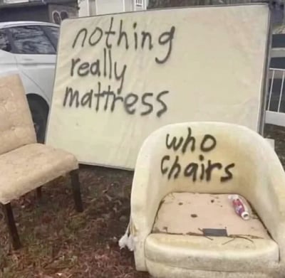 图片展示了一个户外场景，一块竖立的旧床垫上用黑色手写体写着“nothing really mattress”，前方放着一把破旧的椅子，椅背写着“who chairs”。背景有白色汽车和建筑物，地面有落叶，像是被丢弃的家具。文字运用谐音梗：“nothing really mattress”改编自“nothing really matters”（没什么重要的），将“matters”换成“mattress”（床垫）；“who chairs”改编自“who cares”（谁在乎），将“cares”换成“chairs”（椅子），通过家具名称制造幽默效果。