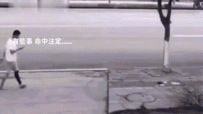 这是一个真人实拍的动态图（GIF），呈现了户外街道的日常场景：一名身着白色短袖、深色长裤的男子正沿着人行道向前行走，画面左侧配有白色文字“有些事 命中注定……”。随着动图的播放，能看到男子行进路径的前方有物品从上方掉落，与文字内容形成呼应，用一种戏谑的方式调侃生活中突如其来的巧合与意外，营造出一种“意外早已注定”的搞笑反差感。