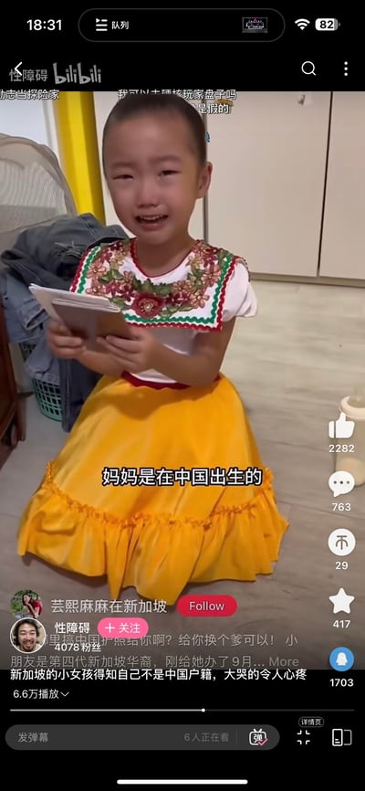 这是B站（bilibili）的一段视频截图，画面里的第四代新加坡华裔小女孩跪坐在地面，面露悲伤大哭，双手拿着物品，画面字幕显示“妈妈是在中国出生的”。视频标题为“新加坡的小女孩得知自己不是中国户籍，大哭的令人心疼”，播放量达6.6万。视频发布者“性障碍”（4078粉丝）在下方留言“哪里搞中国护照给你啊？给你换个爹可以！小朋友是第四代新加坡华裔，刚给她办了9月...”，画面上方还有观众弹幕“我可以去硬核玩家盘子吗”“是假的”，右侧显示视频互动数据：点赞2282、评论763、投币29、收藏417、分享1703，能看出小女孩因自己没有中国户籍而十分难过，对中国有着强烈的身份认同与向往。