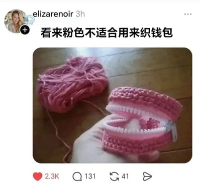 这是一张社交媒体平台的发帖截图，发布者配文“看来粉色不适合用来织钱包”，配图中一只手拿着用粉色毛线钩织完成的钱包，钱包拉开拉链后，粉色的编织外层加白色的拉链齿，外观和颜色都和粉色的上下排假牙极为相似，旁边还摆放着剩余的同色粉色毛线团，视觉上极易让人产生错觉，误将钱包认成假牙，趣味感十足。