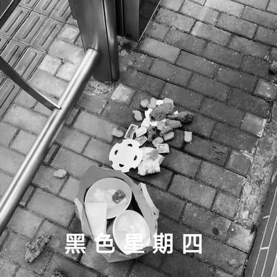 这是一张黑白实拍的场景图，画面展示了户外砖铺地面上，一份外卖被打翻的场景：外卖餐盒倾倒在一旁，炸鸡块、配菜、调料包等食物和包装散落在湿漉漉的砖地上，旁边可见金属栏杆。图片底部配有白色文字“黑色星期四”，化用“黑色星期五”的说法，用外卖打翻的倒霉事件来指代周四的不顺、糟糕，以此吐槽周四的难熬与倒霉，引发同样觉得周四日子不好过的人群共鸣。