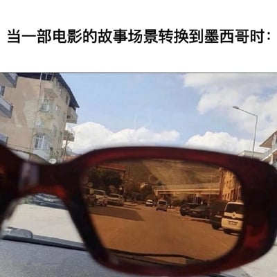 图片上方有文字“当一部电影的故事场景转换到墨西哥时：”，下方是一副太阳镜的特写，镜片中反射出带有明显棕黄色滤镜效果的街景画面，包含建筑物、车辆和远山。通过太阳镜镜片的色调变化，幽默地调侃了电影中常用暖色调滤镜来表现墨西哥场景的刻板印象。