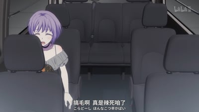 动漫场景截图，展示了一位紫色短发女孩坐在车辆后座，表情痛苦地前倾身体。她穿着灰色露肩上衣，似乎因为吃到太辣的食物而感到不适。画面下方有中文字幕“搞毛啊 真是辣死咱了”和对应的日文翻译。