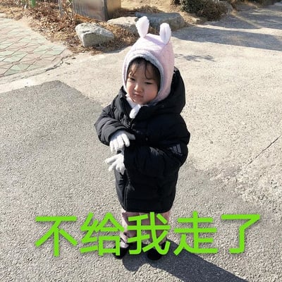 图片中是韩国女童星权律二，她穿着黑色羽绒服，头戴粉色兔耳帽，站在铺有石板的地面上。她双手交叠在身前，表情略带委屈和撒娇，眼神看向一侧，似乎在表达不情愿。图片底部有绿色醒目文字“不给我走了”，生动展现了耍赖不想离开的可爱场景。