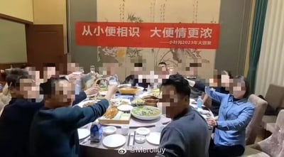 这是一张记录小叶沟2023年大团聚聚餐场景的实拍照片，画面里一群人围坐在摆满各类菜肴的圆形餐桌旁，众人举杯，似乎正在碰杯互动，聚餐气氛看起来较为热烈。所有人物的面部都被打了马赛克，无法看清具体表情。背景的墙面上悬挂着一条红色主题横幅，上面写着“从小便相识 大便情更浓——小叶沟2023年大团聚”，该横幅使用了低俗的谐音梗，将原本表达“从小相识，长大情谊更浓厚”的含义，用低俗词汇替换来制造噱头，格调低下。图片右下角带有微博用户的水印。
