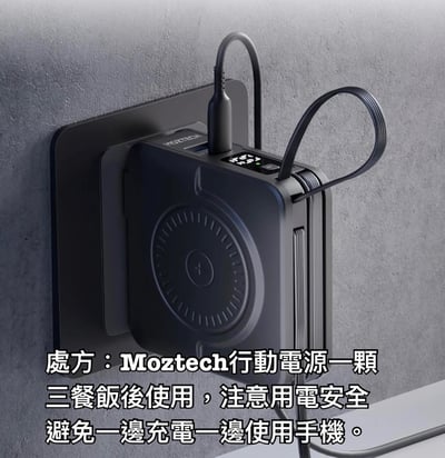 图片展示了一款黑色Moztech行动电源，它被安装在灰色墙面上，顶部连接着一根充电线。电源正面有圆形设计元素和指示灯。图片底部配有文字，以“处方”的幽默形式写道：“Moztech行动电源一颗，三餐饭后使用，注意用电安全，避免一边充电一边使用手机。”通过将日常电子产品使用场景类比为服药处方，营造出轻松搞笑的宣传效果。