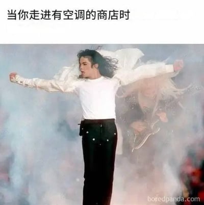 图片上方配有文字“当你走进有空调的商店时”，下方是迈克尔·杰克逊在演唱会现场的经典照片：他穿着白色上衣和黑色裤子，双臂向两侧张开，身体微微后仰，头发因动作飞扬，背景有舞台烟雾效果。通过夸张的肢体语言和表情，幽默地表现了人们从炎热室外进入空调商店时的极度舒适与解脱感。