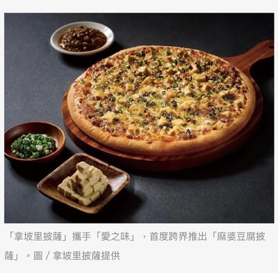 这是一张拿坡里披萨与爱之味联名推出的麻婆豆腐披萨的官方宣传图，画面主体是放置在木质披萨盘上的麻婆豆腐披萨，披萨表面铺满了豆腐块、葱花和麻婆风味酱料，芝士与饼底融合出诱人的质感。画面旁还摆放着这款披萨的核心原料：切好的新鲜葱花、块状豆腐以及麻婆风味酱料，整体画面精致有质感，展现出中西美食结合的新奇创意。
没有双关、谐音梗或暗示内容。