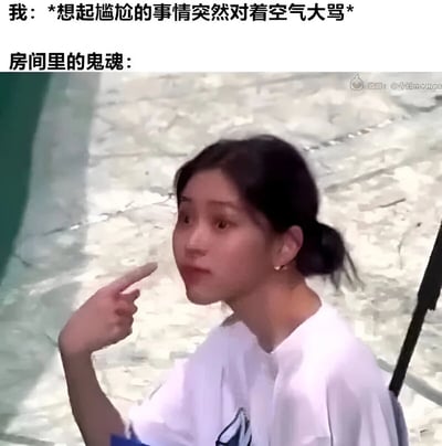 这张梗图由上方文字和下方视频截图组成。上方文字描述了一个生活场景："我：*想起尴尬的事情突然对着空气大骂*"，紧接着是"房间里的鬼魂："。下方截图中是一位扎着马尾、穿着白色T恤的年轻女性，她表情惊讶又带着疑惑，正用手指着侧面，仿佛看到了什么不可思议的事情。图片通过拟人化的鬼魂视角，幽默地表现了当人们突然想起尴尬往事而做出奇怪举动时，可能会让周围旁观者（这里虚构为鬼魂）感到困惑的场景，充满生活气息和搞笑元素。