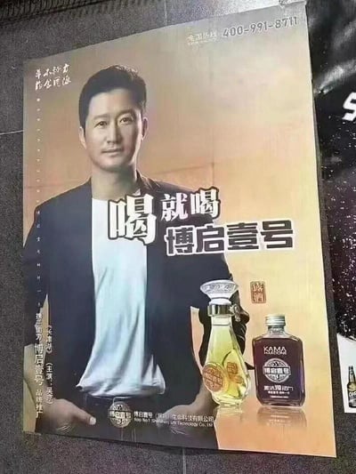 这是一张合成的商业广告海报，主体为演员吴京的半身肖像，搭配醒目的宣传语“喝就喝博启壹号”，同时展示了两款博启壹号的产品酒瓶。海报左侧标注“《长津湖》（主演：吴京） 携手助力博启壹号品牌推广”，底部印有博启壹号（深圳）生命科技有限公司的名称，右上角标注全国热线400-991-8711。该海报属于未经授权的违规合成广告，利用吴京的肖像进行商业宣传，无谐音梗、双关或暗示内容。