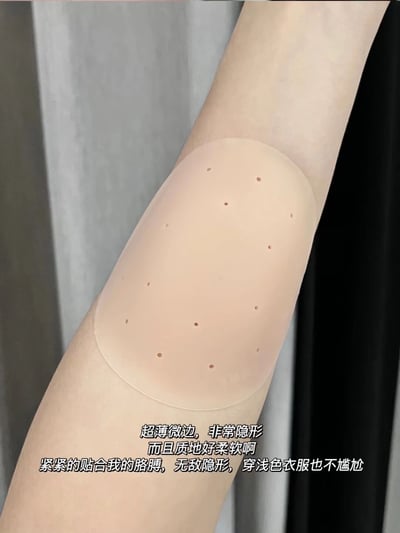 图片展示了一只胳膊上佩戴着米色带透气孔的肘部护垫，护垫呈椭圆形，表面分布多个小孔。图片底部配有文字描述产品特点：超薄微边设计使其非常隐形，质地柔软，能紧密贴合胳膊，即使穿浅色衣服也不会显得尴尬。整体画面聚焦于护垫的隐形效果和舒适度，适合作为产品推荐内容。