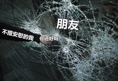图片展示了一只手正伸向破碎的玻璃表面，玻璃呈现出蜘蛛网状的裂痕。手臂上有文字“不擅安慰的我”，手部附近有文字“你还好吗?”，而在破碎玻璃的中心上方有“朋友”二字。这张图片通过破碎玻璃的视觉隐喻，表达了一个不擅长安慰他人的人试图关心朋友的复杂情感。