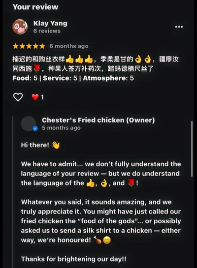 这是一张商家评价页面的截图，用户Klay Yang给Chester's Fried chicken炸鸡店给出了全五星的满分评价，评价正文是一段语义难以理解的中文内容，搭配了点赞、OK手势、玫瑰的表情，还标注了食物、服务、氛围三项均为5分。炸鸡店店主在评价发布1个月后给出回复，表示虽然完全看不懂中文评价的具体内容，但能看懂好评相关的表情符号，还调侃不管评价内容是夸赞炸鸡是“神级美食”，还是要求他们给鸡送丝质衣服，都觉得十分荣幸，感谢用户给他们带来了一天的好心情，整体互动充满趣味反差感。