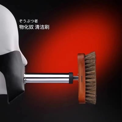 一张搞笑的伪产品宣传图，左侧是一个白色人体模型头部，下半部被黑色物体覆盖，口中含着一把木质手柄的清洁刷。背景是从黑色渐变到鲜红色的设计，左上角有日文'そうぶつ者'和中文'物化奴 清洁刷'的文字。这张图通过将'物化奴'(可能是对'工具人'概念的夸张化)与清洁刷结合，形成一种黑色幽默的效果。