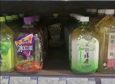 超市冷藏货架上陈列的康师傅系列饮料，包括冰红茶（热带风味）、茉莉绿茶、纯萃零糖茉莉花茶等多款产品，瓶身设计各异，色彩丰富，展现了常见的便利店饮料区场景。