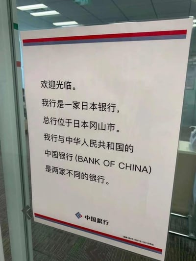 这是一张日本冈山市的「中国銀行」网点张贴的告示，以简体中文撰写，内容为：欢迎光临。我行是一家日本银行，总行位于日本冈山市。我行与中华人民共和国的中国银行(BANK OF CHINA)是两家不同的银行。底部附有该日本银行的标识。由于该行名称与中国的中国银行完全相同，容易造成混淆，因此发布此告示进行明确区分，其中日本的「中国銀行」名称来源于日本的「中国地区」（包含冈山县等区域），和中国国家无关。