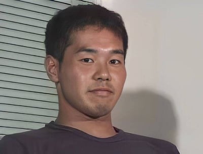 这是一张经典的采访/面试场景照片，画面中人物正襟危坐，背后是百叶窗和白色墙壁。该表情包常用来表达尴尬、难以启齿、无语等情绪。画面布局极具辨识度，常见于各类网络梗图与恶搞场景。

本图通常没有语言内容，仅凭画面表情传达情绪，适用于配字食用。没有明显的双关或谐音梗，但因原图氛围，配以不同文字经常引发幽默感或暗示氛围。