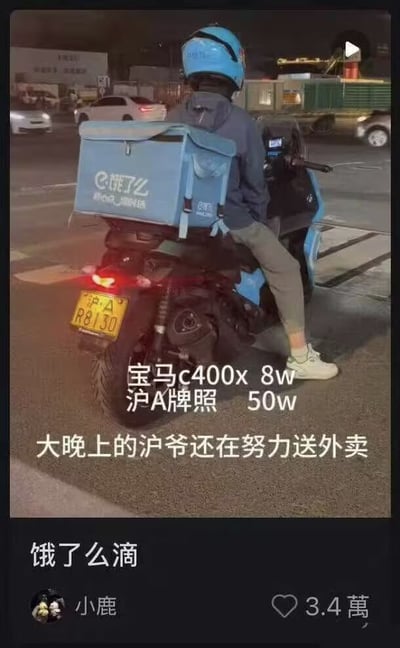 夜间街道上，一名骑着蓝色摩托车的外卖员正准备出发，车尾载着饿了么外卖箱。图片配文突出其座驾为价值8万元的宝马C400X摩托车，以及高达50万元的沪A牌照，调侃“大晚上的沪爷还在努力送外卖”，形成豪车、高价牌照与外卖工作的有趣反差，展现了一种接地气的励志感。