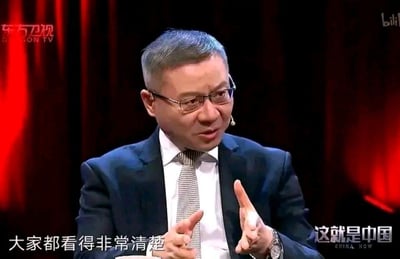 东方卫视《这就是中国》节目中一位戴眼镜的男性演讲者正在发言，背景为红色幕布。屏幕上显示文字'大家都看得非常清楚'。