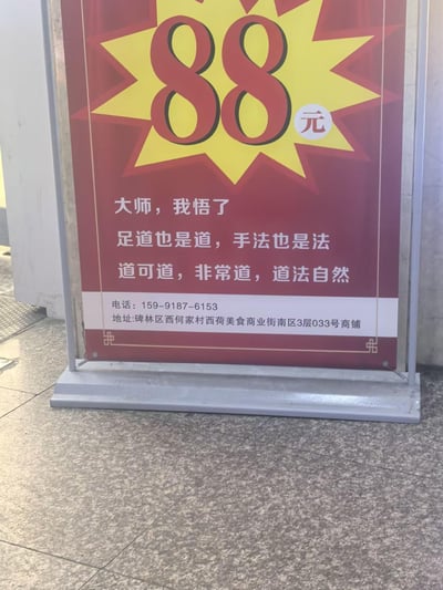 这是一张竖版的线下足道店铺促销展架照片，展架以红黄色为主色调，顶部用醒目的爆炸式图标标注88元的服务价格。下方采用网络流行的“大师，我悟了”句式玩梗，将足道的“道”与《道德经》中的“道”进行双关结合，写出“足道也是道，手法也是法”“道可道，非常道，道法自然”的趣味宣传语，用接地气的搞笑方式吸引顾客。展架底部附带了店铺的联系电话159-9187-6153和详细地址：碑林区西何家村西荷美食商业街南区3层033号商铺，用于线下引流。