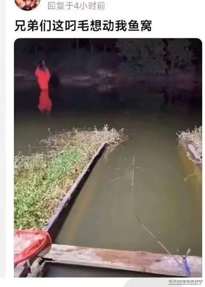这是一张充满趣味的社交媒体截图，画面呈现了一处钓鱼的水边场景：前景水面上伸出钓鱼竿，岸边的红衣路人因视觉错位，看起来仿佛站在水里，发布者配文“兄弟们这叼毛想动我鱼窝”，误以为该路人要闯入自己的钓鱼窝点，制造出荒诞搞笑的乌龙效果，利用视觉错位带来了强烈的反差笑点。