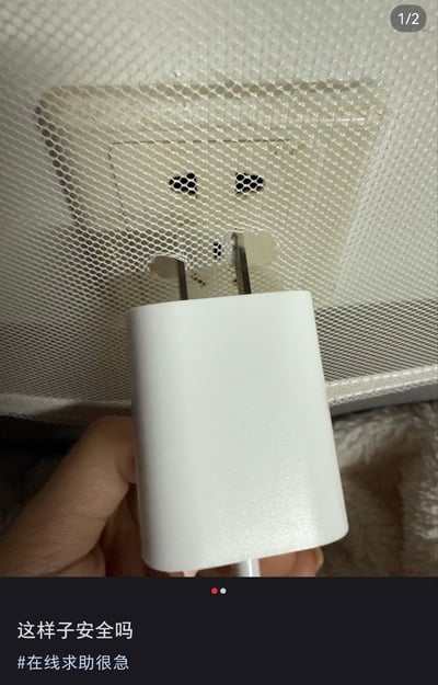 一张实拍照片，展示一只手正拿着白色插头试图插入被白色网罩覆盖的插座中，插头的金属插脚仅部分插入插座孔。图片底部配有文字“这样子安全吗 #在线求助很急”，显然是用户在日常生活中遇到的用电安全问题，寻求网友帮助判断这种情况是否存在安全隐患。