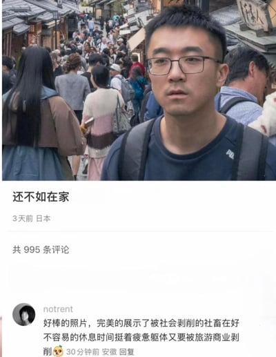 这是一张引发网友共鸣的社交平台动态截图：上方是一位戴眼镜、背背包的男士站在日本拥挤的古街景点前，脸上写满疲惫与无奈，身后是密密麻麻、摩肩接踵的游客人群；下方是他发布的吐槽动态，文案为「还不如在家」，定位显示在日本，3天前发布，动态下有995条评论。其中一条高赞评论精准扎心：「好棒的照片，完美的展示了被社会剥削的社畜在好不容易的休息时间挺着疲惫躯体又要被旅游商业剥削」，戳中了无数社畜假期旅游却遭遇人挤人、花钱找罪受的窘境，引发大量有相似经历的网友共鸣。
