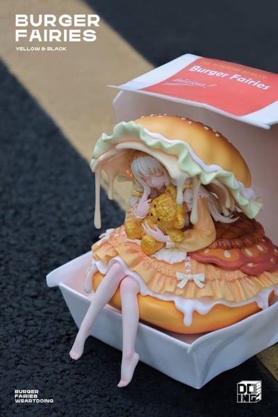 这是WEARTDOING工作室推出的「Burger Fairies（汉堡精灵）-睡美人」黄黑配色款手办的实拍图。手办将少女与汉堡元素创意结合：闭着双眼的恬静少女抱着小熊玩偶，身体融入汉堡结构中，上半身被带有流淌芝士效果的汉堡面包顶覆盖，裙摆与汉堡的肉饼、酱料等细节融合，裸露的双腿自然垂在汉堡外，整体被放置在仿真汉堡盒中。手办细节精致，芝士、酱料的流淌效果逼真，风格梦幻治愈，完美呈现了“睡美人藏在汉堡中”的创意设定。