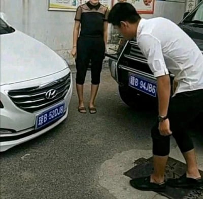 图中呈现了一个极具趣味的视觉错位场景：前景的男士弯腰低头，他的下半身与中间女士的上半身恰好拼接，形成了“男士拥有女士双腿”的错觉，仿佛女士的下半身“消失”了。同时，两辆车的车牌也暗藏谐音梗：白色现代车的车牌“琼B·52DJ8”谐音“我不爱DJ8”，黑色车的车牌“赣B·94JB6”谐音“就是JB6”，双重笑点拉满，让人忍俊不禁。