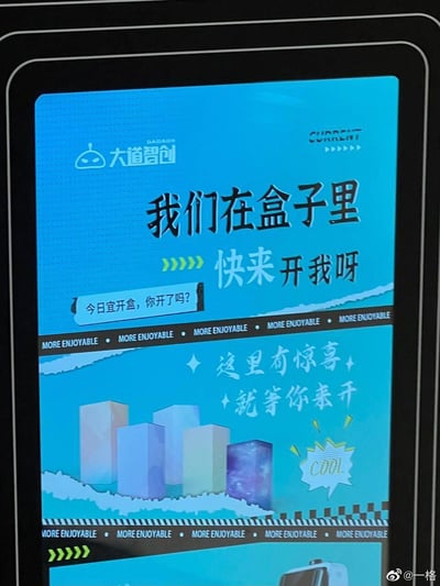 这是大道智创推出的开盒活动推广界面，整体采用蓝绿色活泼风格，界面上方以醒目的标语“我们在盒子里，快来开我呀”吸引用户，搭配对话气泡文案“今日宜开盒，你开了吗？”进一步引导，下方用“这里有惊喜，就等你来开”的文案配合盒子样式的图形，传递出开盒有惊喜的活动信息，整体氛围热情活泼，旨在吸引用户参与开盒活动，图中无谐音梗、双关或暗示内容。