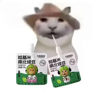 图片背景是一只戴着棕色帽子的灰白猫咪，面部表情平静，正用吸管吸食前景中的饮料。前景摆放两袋绿色包装的“九阳豆浆”产品，包装印有“哈基米南北绿豆”字样及卡通猫咪形象——左侧猫咪戴绿色头盔呈打坐姿势，右侧猫咪戴耳机手持吸管饮用，均标注“鲜磨”“0脂肪”“净含量150g”等信息。整体通过将网络热词“哈基米”（猫的爱称）与知名豆浆品牌结合，模拟趣味联名包装，营造搞笑可爱的氛围。