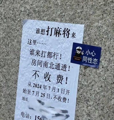 图片中展示了一张贴在粗糙地面上的白色广告纸，上面用黑色大字写着打麻将的邀请信息："谁想打麻将来这里……谁来打都行！房间南北通透！不收费！从2024年7月1日开始至7月25日，不收费！"。广告下方的地址和联系电话部分被模糊处理。在广告纸的右侧，贴着一张蓝色小卡片，上面有一个卡通警察形象，并配有文字"小心同性恋"。这种将休闲娱乐邀请与歧视性内容并置的组合形成了强烈反差。
