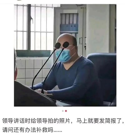 这是一张记录职场尴尬乌龙事件的照片：一位佩戴蓝色口罩的职场领导坐在会议桌后，正处于讲话状态，由于拍摄角度的问题，面前的两个立式麦克风恰好对准领导的脸部位置，视觉上看起来像是完全挡住了领导的脸。照片下方配文说明这是要用于发布简报的领导讲话照片，拍摄者正焦急询问补救办法，生动展现了职场中给领导拍照时容易遇到的小窘境，充满了搞笑的氛围。