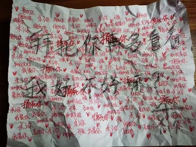 这是一张皱巴巴的纸张，上面用红色笔密集写满了极端矛盾的文字：既有「喜欢你」「我爱你」「和我交往」「可爱」这类充满爱慕的温柔表述，又反复重复「捅死你」「杀了你」这类带着暴力威胁的语句。纸张中间还用黑色笔涂改后，写出了混乱的「你捅死你多看看」「我好喜欢你」字样，整体文字密密麻麻堆叠，构图杂乱无章，传递出一种偏执又极度矛盾的情绪，像是偏执型爱慕者在极端情绪下的内心写照，图中没有双关、谐音梗或暗示内容。