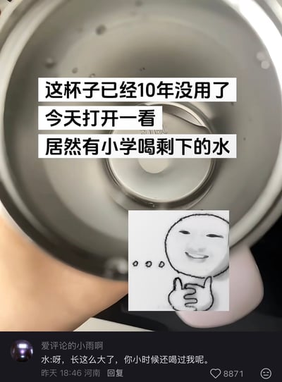 图片展示了一个金属杯子的内部特写，杯中有少量残留液体和水珠。上方叠加文字写道：“这杯子已经10年没用了 今天打开一看 居然有小学喝剩下的水”，底部配有一条网友评论：“水:呀，长这么大了，你小时候还喝过我呢。”，并插入一个微笑竖大拇指的卡通表情包。整体通过夸张的生活场景和拟人化的神评论制造幽默效果，展现了生活中荒诞又搞笑的瞬间。