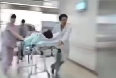 这张梗图主体是经过动态模糊处理的医院急救场景，数名身着医护服装的人员正推着载有患者的担架床在走廊快速前进，充满紧张感。搭配的文案利用谐音梗做状态对比：五一假期前五天大家满心期待假期，兴奋喊着“五一五一五一”满是快乐；假期结束后身心俱疲的状态就像要被紧急送医，对应救护车鸣笛的谐音“一五一五一五”，精准调侃了当代人经历假期后患上节后综合征、状态极差的普遍感受。
