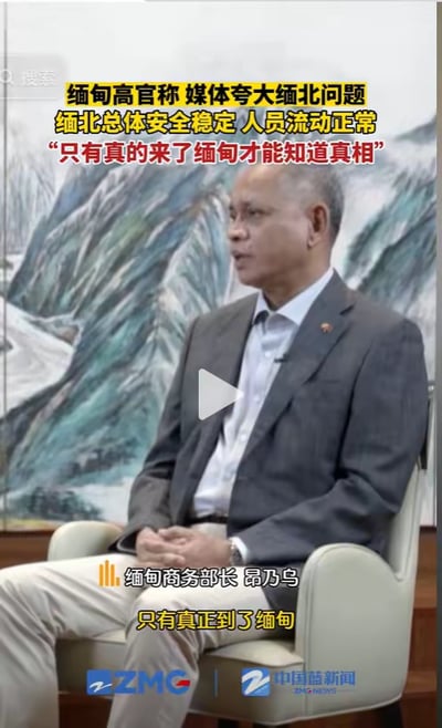 这是一段竖屏新闻采访的视频截图，画面主体是缅甸商务部长昂乃乌，他身着灰色西装外套搭配浅色长裤，坐在椅子上双手交握置于腿上，神情严肃地接受采访。图中添加了黄色字幕，上方内容为：“缅甸高官称 媒体夸大缅北问题 缅北总体安全稳定 人员流动正常 ‘只有真的来了缅甸才能知道真相’”，画面中间偏下标注了人物身份“缅甸商务部长 昂乃乌”，下方还有他的发言内容“只有真正到了缅甸”。画面底部带有“ZMG 中国蓝新闻”的水印，整体是官方新闻采访的正式场景，传递了该官员针对缅北安全问题的相关表态。