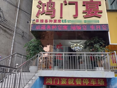 这是一张线下餐饮店铺的实拍照片，门店的主招牌以浅黄色为底，搭配深红色立体大字写着“鸿门宴”，招牌下方的小字标注该店承接各种宴席，同时附有被部分打码的联系电话；招牌下方的LED滚动屏同样显示店铺承接结婚宴、生日宴等各类宴席。门店入口有台阶和不锈钢护栏，玻璃门上贴有红色的“欢迎”字样，入口下方还设有红色指示牌标注“鸿门宴就餐停车场”。由于“鸿门宴”是中国历史上著名的暗藏风险、不怀好意的宴席典故，被用作餐饮店名形成了强烈的反差感，颇具趣味性。