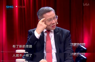这是东方卫视政论节目《这就是中国》的上下分栏视频截图，画面中学者张维为身着西装红领带，戴着眼镜，用食指指向自己的头部，正在发表观点。上下两部分分别配文“有了新的思路”和“人就不一样了”，传递出思维观念的转变会带来自身改变的观点，常被用来表达观念更新后带来的变化。