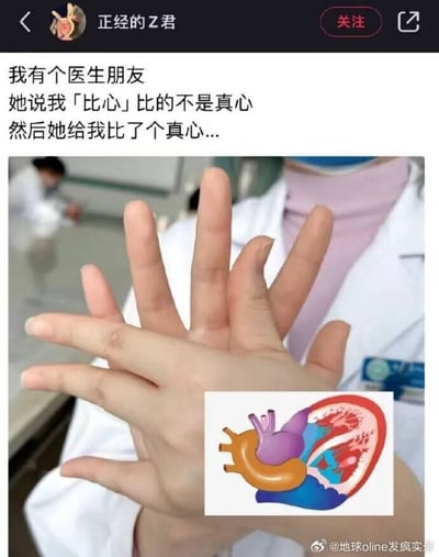 这是一张在社交平台传播的趣味梗图，采用图文混排的形式，上方是博主发布的配文，内容为：「我有个医生朋友 她说我「比心」比的不是真心 然后她给我比了个真心...」。配图部分是一名身着白大褂、佩戴口罩的医护人员，双手交叠比出特殊手势，该手势的轮廓和右下角搭配的人体心脏解剖示意图外形高度吻合，用医护专业视角对「比心」做了另类解读，通过日常流行手势和专业知识的反差制造笑点。背景为医院类的工作场景，还能看到其他穿着白大褂的工作人员，图片右下角带有「@地球online发疯实录」的水印。