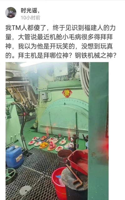 这是一张社交媒体动态截图，用户“时光谣”分享了自己在航海工作中的新奇经历：船上的大管称机舱主机近期小故障频发，需要祭拜神灵，用户原本以为是玩笑，没想到对方真的在绿色的机舱主机前摆放了水果、肉类等供品，点上蜡烛，还贴了倒福字进行祭拜。用户对此十分惊讶，调侃拜主机是在拜钢铁机械之神，画面将民俗祭拜与工业机械结合，充满反差感，体现了福建民俗在航海职场中的有趣应用。