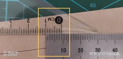 图片展示了两把尺子在绿色切割垫上的测量场景。上方为透明塑料尺子，标有'CM'及0、1、2、3厘米刻度；下方为金属尺子，显示10、20、30、40厘米刻度。黄色方框特意高亮了透明尺子的0厘米刻度位置，该位置与金属尺子的10厘米刻度处对齐。背景中的绿色切割垫带有蓝色网格线，右上角可见数字'60'标识。图片底部有水印信息，显示由MEIZU 16s拍摄及知乎用户@纽币珀拉斯发布。